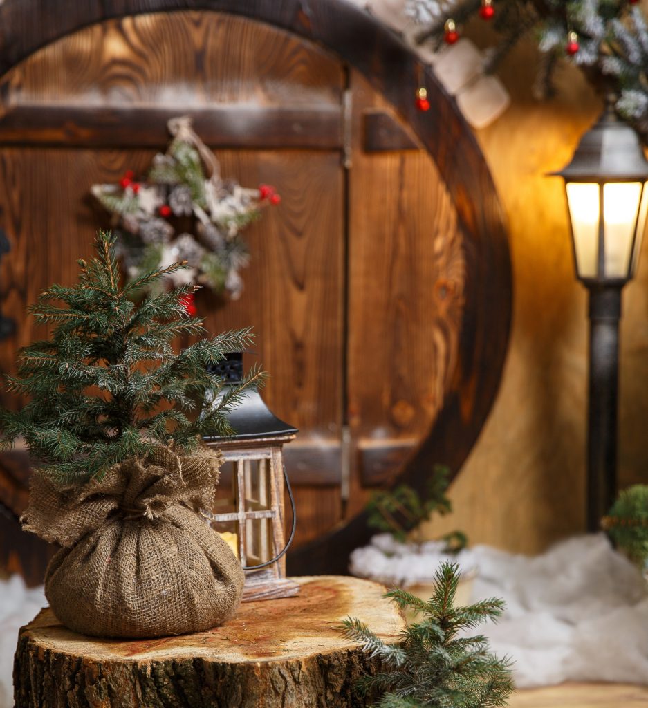 Festive decorations in the lamplight, outside a round, wooden door, hung with a holly star.