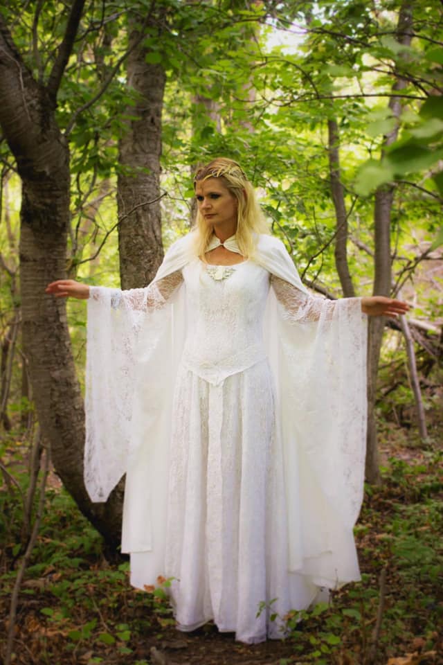 Fan Mindy in a gorgeous Galadriel costume she made. She is standing in a wooded clearing, looking like she's in Lothlorien!