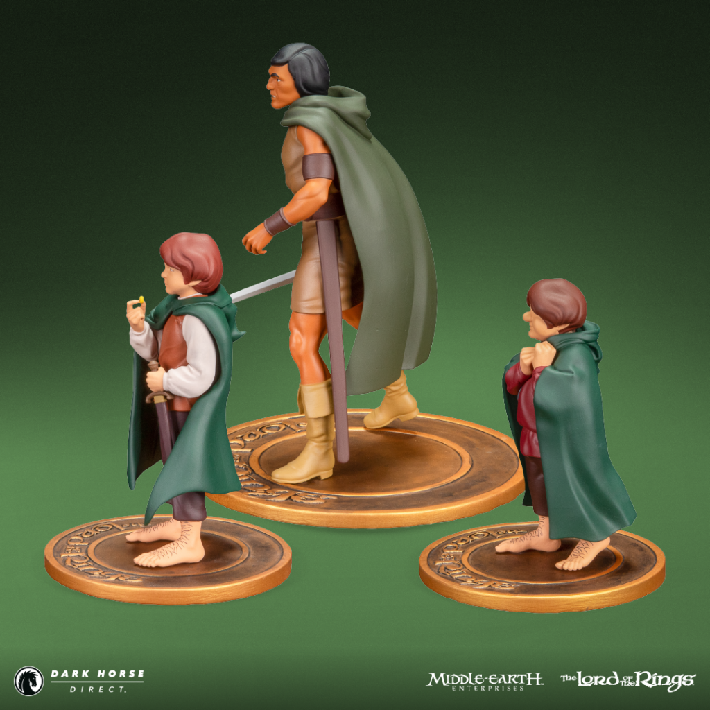 Three Lord of the Rings action figures: a tall warrior with a green cape and sword, flanked by two hobbits in green cloaks on round bronze bases.