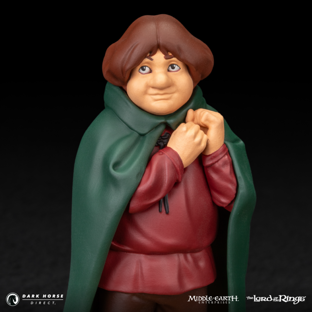 Clay figurine of a Hobbit with brown hair in a green cloak, clasping hands at chest, wearing red tunic.