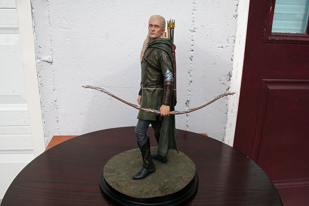 Life-size Legolas action figure with bow and quiver, standing on a circular display pedestal.