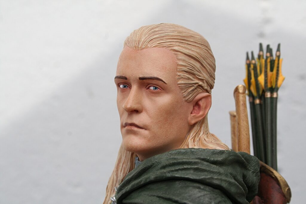 Close-up of a blonde-haired statue wearing a green cloak, with a quiver of arrows visible behind the head.