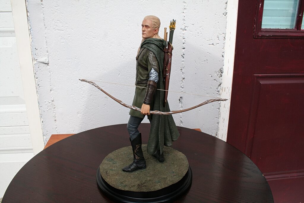 Poseable Legolas action figure with bow and quiver, standing on a round display base.