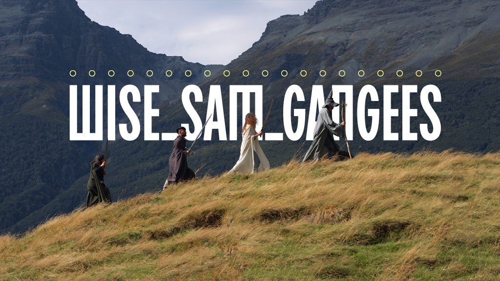 Group of people in cloaks walking along a grassy hillside with mountains in the background, oversized text overlay reads 'WISE SAIL GANGES'.