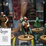 Miniature The Lord of the Rings characters in a glass display case, including hobbits and warriors on round bases.