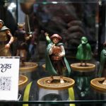 Lord of the Rings figurines in cloaks standing on round bases inside a glass display case, with a sign reading 'Lord of the Rings' nearby