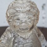 Close-up of a clear glass figurine of a childlike knight, holding a sword