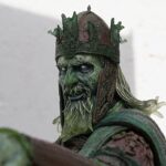 Close-up of a green dragon statue wearing an ornate crown and matching armor with intricate patterns.