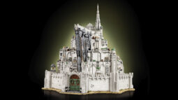 LEGO model of a grand white fortress with a tall central spire, green domes, and an arched entry on a tan base.