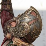Close-up of an ornate medieval helmet with decorative scrollwork and rivets.