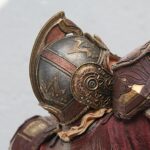 Close-up of ornate bronze armor with decorative engravings on a shoulder and helmet area