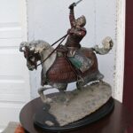 Statue of a medieval knight in ornate armor on an armored horse, raising a sword overhead.