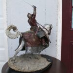 Statue of a medieval knight in full armor atop a armored horse, raising a sword overhead.