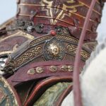 Close-up of red and gold decorative armor plates with intricate patterns and a red gem centerpiece