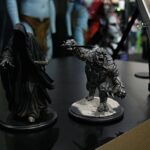 Two black dragon figurines posed on display stands in a storefront case, with a blurred background shop scene behind.