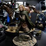 Figure of Eowyn, Shieldmaiden of Rohan, in detailed armor and green cloak on a rocky display base at a convention showtable ground scale model.