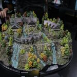 Detailed model of Rivendell with cascading waterfalls, pine trees, and Gothic architecture on a rocky hillside.