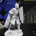 Gray armored knight figure with sword and shield standing on a rocky pedestal in a diorama display.