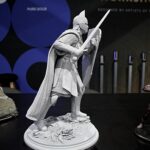 Grey knight action figure with raised sword and shield on rocky base, museum display backdrop of blue circles behind him