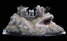Scale model of a ruined stone castle on a rocky hill with a glowing cave entrance deep in the rock formation.