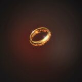 Glowing gold ring with fiery inscriptions hovering in a dark red background.